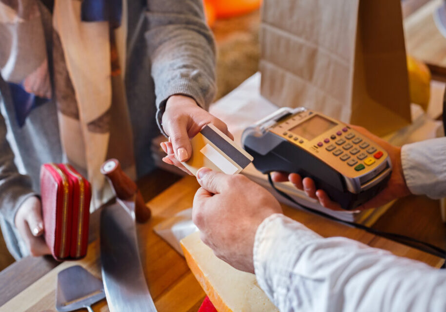 Credit card payment service. Customer paying for order of cheese in grocery shop.