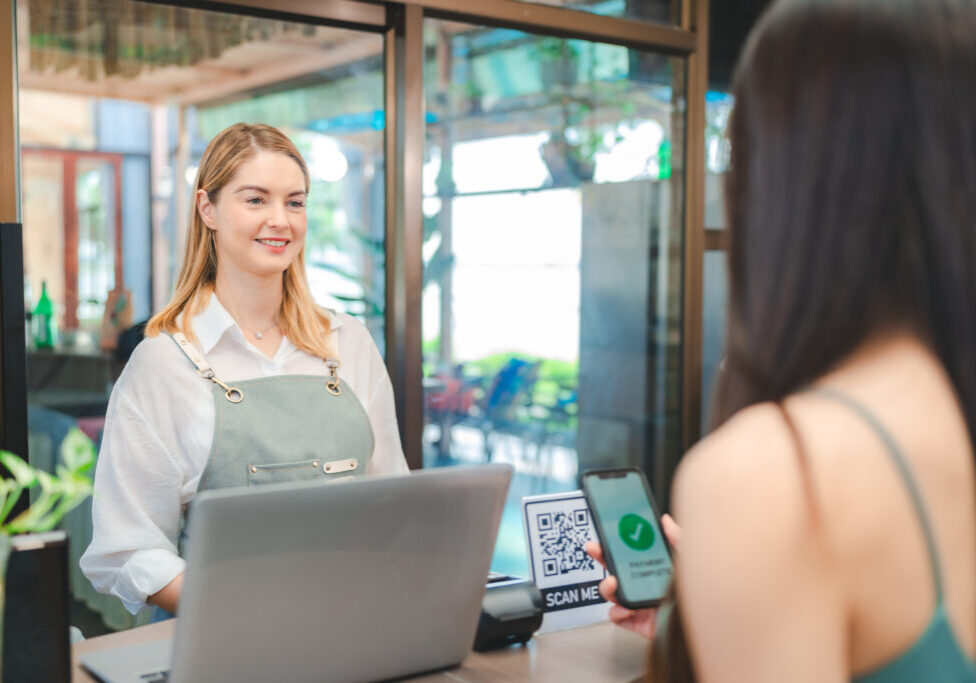 Smiling waitress wear apron take order talk to clients serving restaurant guests choosing food drinks menu in cafe coffeehouse bar, waiting staff, good customer service, cashier serving customers