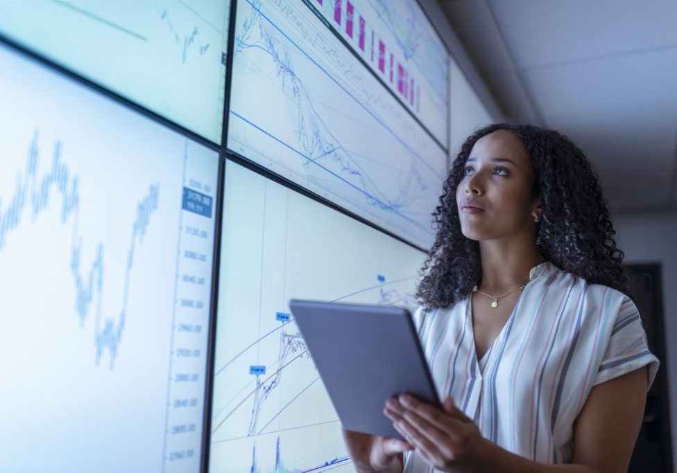 UK, York, Businesswoman with tablet looking at charts on interactive screens