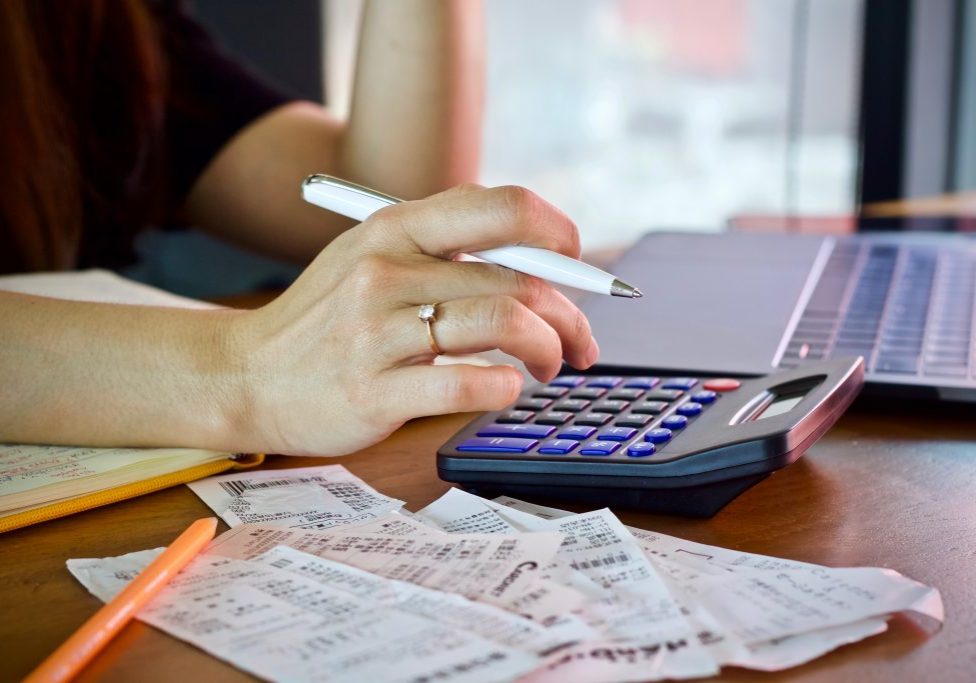 woman-holding-bill-using-calculator-and-calculate-2024-11-29-14-10-27-utc